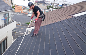 屋根の上で点検と面積などを採寸する業者の人